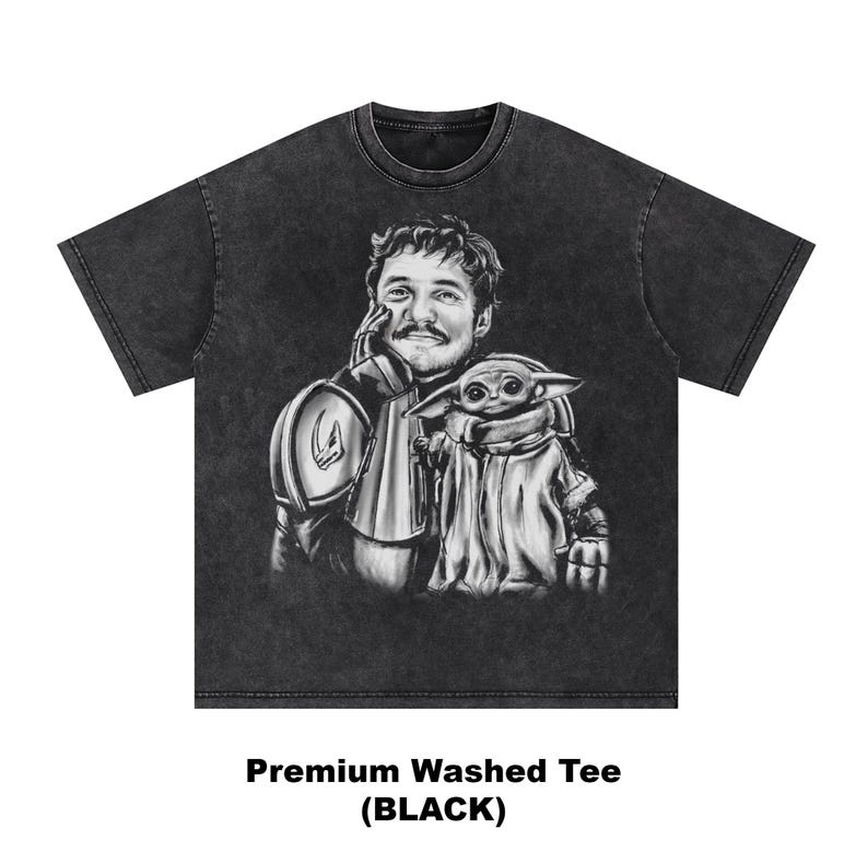 Puede incluir: Camiseta negra lavada con una ilustraci&oacute;n en escala de grises de un hombre y una peque&ntilde;a criatura. El hombre lleva una armadura y la criatura est&aacute; envuelta en una capa. El texto "Premium Washed Tee (BLACK)" est&aacute; en la parte inferior.