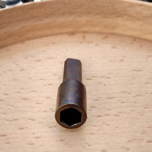 以下が含まれることがあります： 黒い持ち手と「But First, Coffee」の文字が黒い太字でプリントされた白いセラミックマグ。マグカップは木製の表面に置かれています。マグカップの高さは約10cmです。