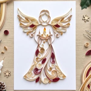 May include: A paper quilling art piece on a white background depicting an angel with large wings. The angel is crafted from coiled paper strips in shades of cream, beige, and deep red, holding a small candle with a bright yellow flame.
