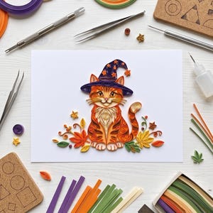 May include: A paper quilling art piece on white paper featuring an orange tabby cat wearing a purple witch hat with orange stars. The cat is surrounded by colorful paper quilled autumn leaves, berries, and small stars, with crafting tools nearby.