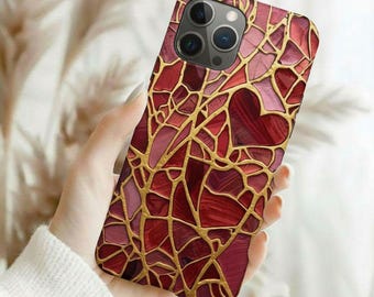 Puede incluir: Funda de teléfono inteligente con un diseño de vidriera en tonos rojos y rosas, acentuada con líneas doradas. La funda presenta una forma de corazón y un recorte para cámara de lentes múltiples.