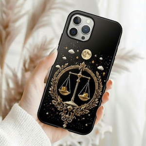 May include: Black smartphone case featuring a gold Libra scale design. The case has a glossy finish with a celestial theme, including a full moon, clouds, and stars. The Libra scale is set within a decorative gold wreath.