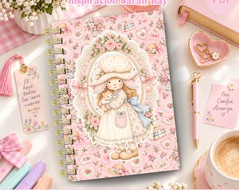 Könnte beinhalten: Ein spiralgebundener Wochenplaner für 2027 mit rosa Blumenmuster und einer zentralen Illustration eines Kindes mit Kätzchen. Das Cover enthält den Text AGENDA SEMANAL 2027 und Inspiración Sarah Kay, ergänzt durch ein passendes Lesezeichen, einen Stift und einen Notizblock.