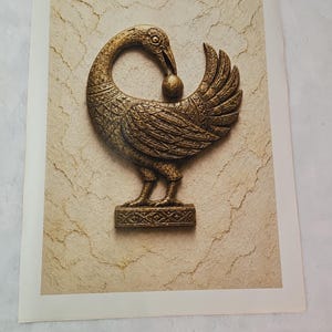 a close-up of a decorative bronze sculpture of a bird, possibly a swan or goose, with a ball in its beak.