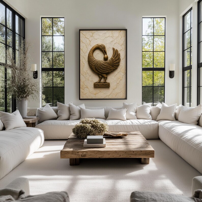 a spacious and well-lit living room with large windows, white sofas, and a wooden coffee table. A large gold sculpture of a bird is displayed on the wall above the sofas, and the room is decorated with various plants and other decorative items.
