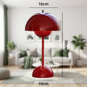 K&ouml;nnte beinhalten: Eine rote Tischlampe mit gl&auml;nzender Oberfl&auml;che. Die Lampe hat einen abgerundeten Sockel, einen schlanken Stiel und einen gro&szlig;en, halbkugelf&ouml;rmigen Schirm. Die Lampe ist 30 cm hoch, 16 cm breit und der Sockel hat einen Durchmesser von 10 cm. Dekorative Leuchte.