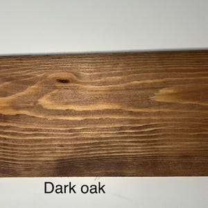 K&ouml;nnte beinhalten: Ein rechteckiges St&uuml;ck dunkles Eichenholz mit sichtbarer Holzmaserung. Das Holz hat eine satte, braune Farbe mit helleren Streifen und &Auml;sten. Der Text "Dark oak" ist unten im Bild in Wei&szlig; gedruckt.