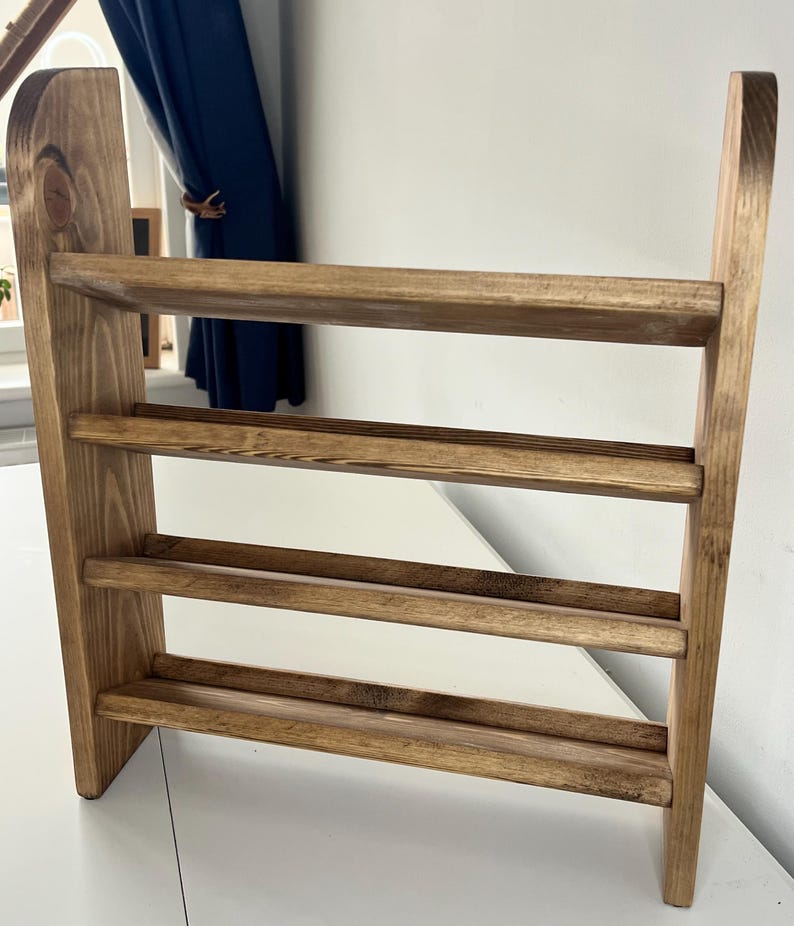 K&ouml;nnte beinhalten: Ein Schuhregal aus Holz mit drei Ablagen. Das Regal ist aus hellbraunem Holz gefertigt und hat ein schlichtes, minimalistisches Design. Die Ablagen werden von vertikalen Seitenteilen getragen.