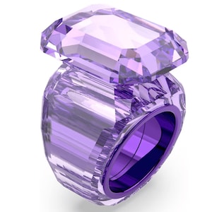 Könnte beinhalten: Ein klobiger Ring aus durchscheinendem, hellviolettem Material mit einem großen, rechteckigen, facettierten Stein an der Oberseite. Der Ring ist dick und ebenfalls facettiert, mit einem tiefvioletten Innenfutter, das durch das Material sichtbar ist.