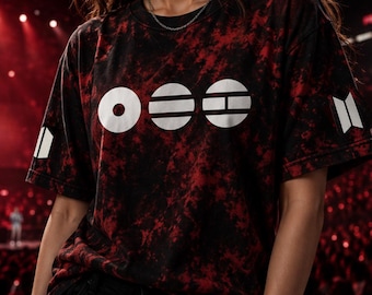 Op de afbeelding: Een t-shirt met korte mouwen en een ronde hals met een zwart en rood tie-dye patroon. Op de borst staan drie witte cirkelvormige grafische symbolen en op elke mouw staat een wit geometrisch logo bestaande uit twee verticale trapeziumvormen.