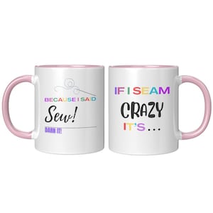 May include: Two white ceramic mugs with pink handles and interiors. One mug has the text "BECAUSE I SAID Sew! Darn It!" and a needle and thread graphic. The other mug says "IF I SEAM CRAZY IT'S..." in colourful letters.