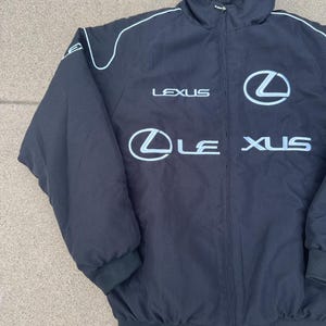 Pu&ograve; includere: Giacca nera con zip, finiture bianche e logo Lexus in bianco. La giacca ha un collo alto e polsini e orlo a coste. Il logo Lexus &egrave; visualizzato sul petto e sulla parte anteriore.