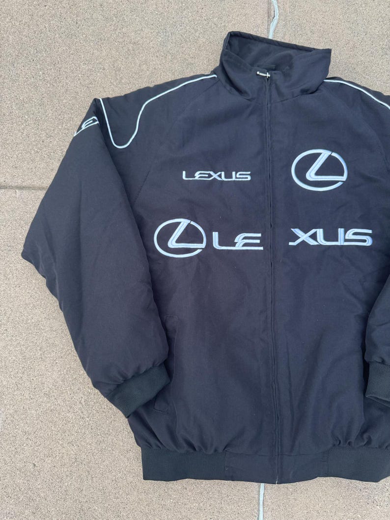 Pu&ograve; includere: Giacca nera con zip, finiture bianche e logo Lexus in bianco. La giacca ha un collo alto e polsini e orlo a coste. Il logo Lexus &egrave; visualizzato sul petto e sulla parte anteriore.