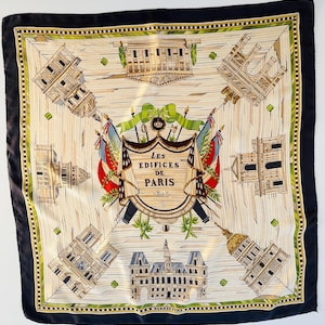 May include: Square silk scarf with a black border and a cream-coloured centre. The scarf features illustrations of Parisian buildings, a central crest with the text "Les Edifices de Paris 1866", and decorative elements in green, red, and blue.