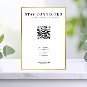 Könnte beinhalten: Ein weißes Schild mit goldenem Rahmen, das den Text "STAY CONNECTED" und einen QR-Code zeigt. Darunter stehen "NETWORK" und "PASSWORD". Unten steht "JOSH & SARAH 08.08.2026".