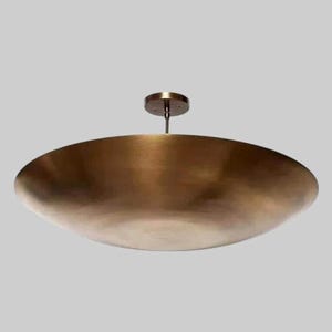 May include: A large, bronze-coloured, bowl-shaped ceiling light fitting. The fitting is suspended from a small, circular ceiling mount. The light has a smooth, metallic finish and a wide, shallow bowl design, suitable for modern interiors.