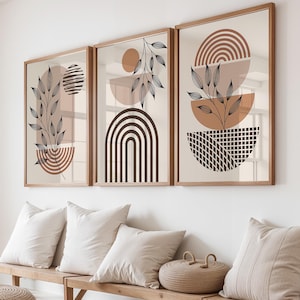 May include: Three framed wall art prints featuring abstract geometric shapes and black line-drawn botanical leaf motifs in shades of terracotta, beige, and dark brown. The artwork displays semi-circles, arches, and grid patterns on a light background.