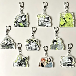 May include: A collection of nine clear acrylic keychains featuring black and white manga-style illustrations of pairs of characters with accents of lime green. Each keychain is attached to a silver-toned metal lobster clasp and split ring.