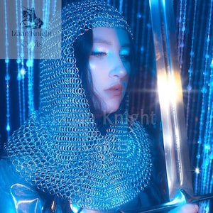 May include: A person wearing a chainmail hood and holding a sword. The image is bathed in blue light, with the text "Izaan Knight Crafts" visible in the upper left corner and "Izaan Knight" in the lower right corner.