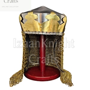 Può includere: Elmo medievale con corona dorata e cotta di maglia. Esposto su un supporto rosso su sfondo bianco. Il testo "Izaan Knight Crafts" è visibile in alto a sinistra. Oggetto storico.
