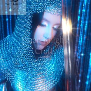 May include: A person wearing a chainmail hood and a matching chainmail garment. A long sword is held in the right hand. The image has a blue and silver colour scheme. The text "Izaan Knight Crafts" is visible in the upper left corner.