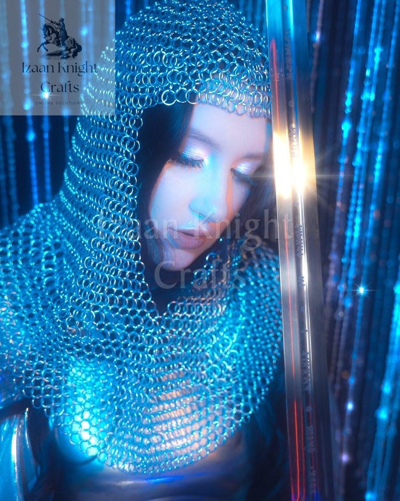 May include: A person wearing a chainmail hood and a matching chainmail garment. A long sword is held in the right hand. The image has a blue and silver colour scheme. The text "Izaan Knight Crafts" is visible in the upper left corner.