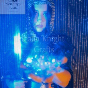 May include: A person wearing a chainmail hood and armour, holding a glowing blue sword and a ball of blue light. The image has a blue and orange colour scheme, with the text "Izaan Knight Crafts" visible in the upper left and centre.