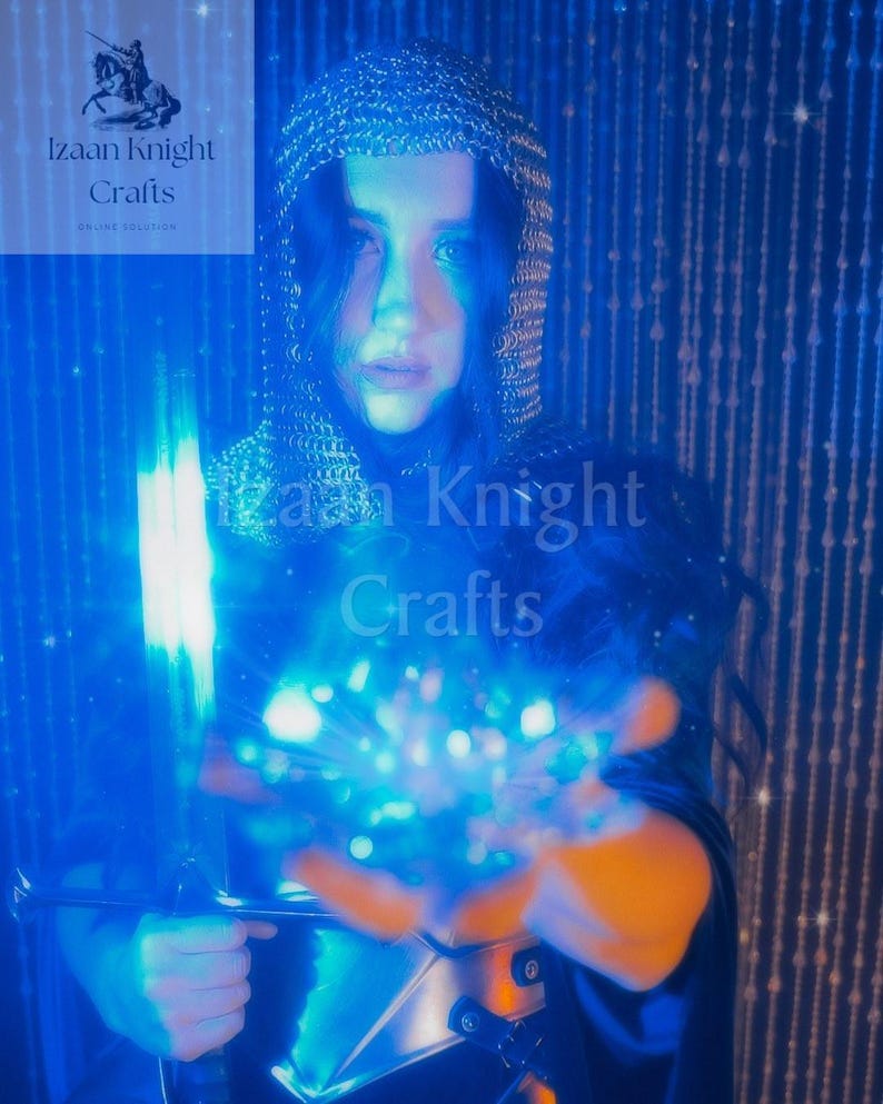 May include: A person wearing a chainmail hood and armour, holding a glowing blue sword and a ball of blue light. The image has a blue and orange colour scheme, with the text "Izaan Knight Crafts" visible in the upper left and centre.