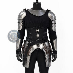 May include: A suit of armor featuring a polished steel gorget, articulated pauldrons, and tassets with brown leather straps. The ensemble includes a black corset with silver-toned metal buckles, black gloves, and a black long-sleeved ribbed shirt.