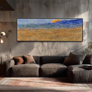 May include: A panoramic landscape painting featuring a golden wheat field in the foreground under a vibrant orange sun and swirling blue sky. The artwork is framed in black and displays thick, textured brushstrokes throughout the composition.