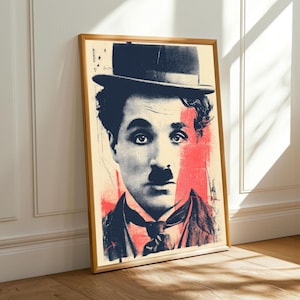 Può includere: Stampa pop art incorniciata con un ritratto di Charlie Chaplin nei toni del nero, rosso e crema. L'immagine mostra Chaplin con bombetta e abito, con un effetto pennellata rossa sul lato destro. La stampa è in una cornice dorata.