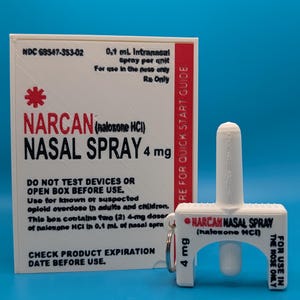 May include: A white rectangular box labeled NARCAN NASAL SPRAY 4 mg with red and black text, accompanied by a small white plastic replica of the nasal spray device featuring a metal keyring and matching black text on a white background.