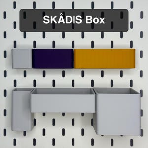 Peut inclure: Un panneau perforé blanc avec divers boîtes et conteneurs de rangement gris, violets et jaunes. Le texte "SKÅDIS Box" est affiché en haut. Les boîtes sont conçues pour être fixées au panneau perforé.