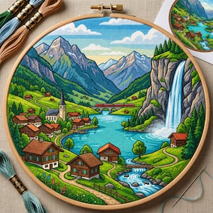 Puede incluir: Un bastidor de bordado circular de madera que contiene un patrón de punto de cruz de un paisaje montañoso. La escena muestra un pueblo con casas marrones, una iglesia, un lago azul, una cascada, un tren rojo sobre un puente y colinas verdes.