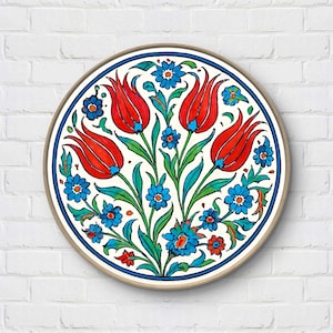 May include: Circular wall art with a floral pattern. The design features red tulips, blue flowers, and green leaves on a white backdrop. It is framed with a blue border and a wooden frame. The artwork is a decorative piece.