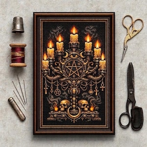 May include: A framed cross-stitch artwork featuring a golden candelabra with seven lit candles, a central pentagram, an eye symbol, and two skulls. Surrounding the frame are a metal thimble, a wooden spool of red thread, four needles, and two scissors.