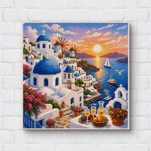 Peut inclure: Une broderie au point de croix représentant un village côtier grec avec des bâtiments blancs, des dômes bleus, des moulins à vent et des fleurs roses. La scène montre un coucher de soleil sur la mer avec des voiliers et une table au premier plan.