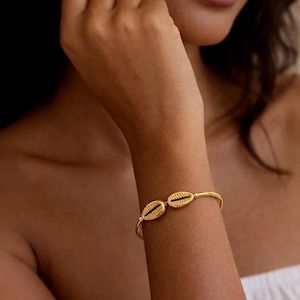 Puede incluir: Una taza de cerámica blanca con asa negra y el texto "But First, Coffee" en negrita negra. La taza se encuentra sobre un fondo borroso, sugiriendo un ambiente acogedor.