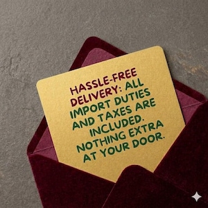 May include: A gold card with the text "HASSLE-FREE DELIVERY: ALL IMPORT DUTIES AND TAXES ARE INCLUDED. NOTHING EXTRA AT YOUR DOOR." is inside a burgundy envelope. The background is a textured gray.