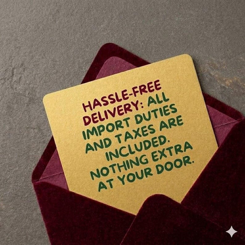 May include: A gold card with the text "HASSLE-FREE DELIVERY: ALL IMPORT DUTIES AND TAXES ARE INCLUDED. NOTHING EXTRA AT YOUR DOOR." is inside a burgundy envelope. The background is a textured gray.