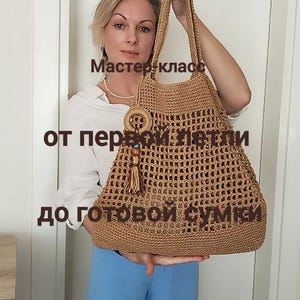 Puede incluir: Un bolso tote tejido a ganchillo en color marrón claro, con un anillo decorativo y una borla. El bolso tiene un patrón tejido y se sujeta por sus asas. El texto en ruso dice "Master class from the first loop to the finished bag."