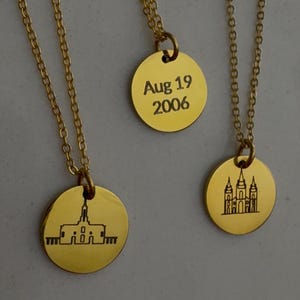 May include: Gold-colored necklaces with round pendants. One pendant has the date "Aug 19 2006" engraved. The other two pendants feature architectural line drawings. The necklaces have delicate chain links.