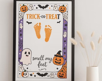 May include: A framed Halloween-themed print featuring orange baby footprints in the center, the text TRICK-OR-TREAT at the top, and the text smell my feet at the bottom. The border is decorated with orange pumpkins, white ghosts, black bats, and spiderwebs.