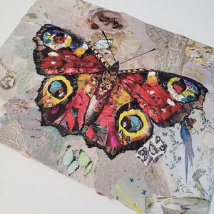 May include: A colorful butterfly collage with red, yellow, and blue accents. The butterfly is made of paper and has a textured surface. The background is a light gray with a variety of patterns.