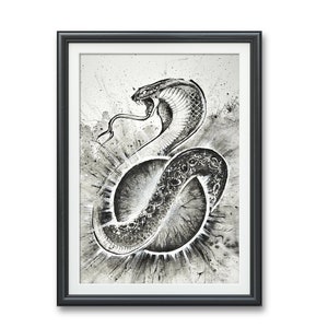 May include: Black and white ink drawing of a cobra snake with its hood raised, framed in a black frame. The snake is coiled around a circle with a radiating pattern.