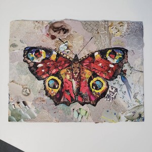May include: A colorful butterfly collage with red, yellow, and blue accents. The butterfly is made of paper and is surrounded by other paper scraps, including a small bird and a watch.