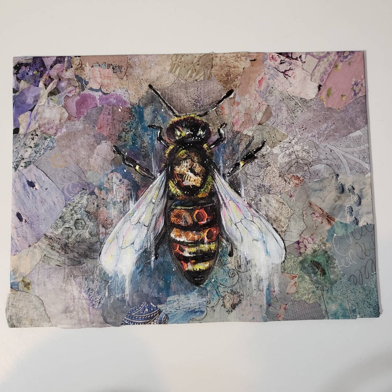 Puede incluir: Una pintura de t&eacute;cnica mixta de una abeille con rayas negras y amarillas y acentos naranja y rojo. La abeja est&aacute; pintada sobre un fondo texturizado con un collage de papel y pintura.
