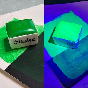 May include: A green watercolor paint pan labeled "Sludge" glows bright green under a blacklight.
