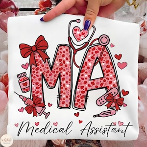 Puede incluir: Camiseta blanca con las letras "MA" en patrones de corazones rosas y rojos, junto con ilustraciones médicas. Las palabras "Medical Assistant" están escritas en cursiva en la parte inferior.