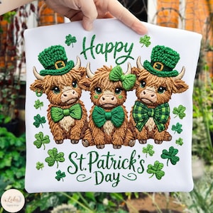 May include: White t-shirt with an embroidered design of three Highland cows wearing green bow ties, hats, and shamrocks. The words "Happy St. Patrick's Day" are embroidered in green. A festive design for St. Patrick's Day.